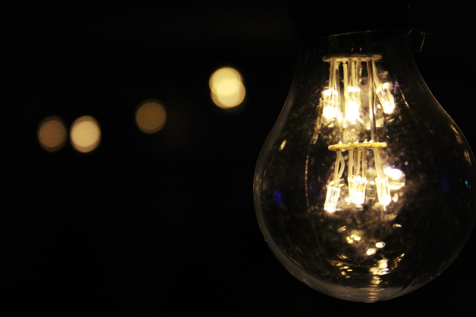 Leuchtende Glühlampe vor dunklem Hintergrund
